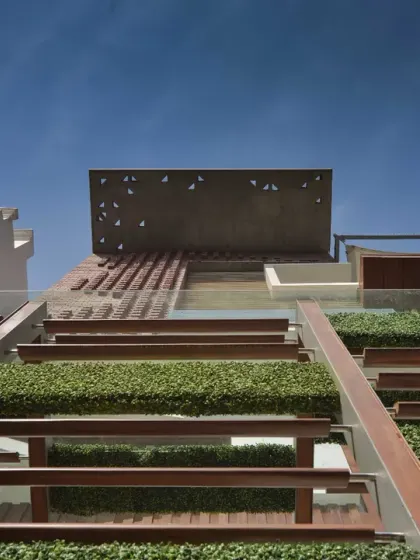 The exterior of the Kavyam Residence blends traditional and modern elements. A brick jaali pattern adds texture and allows for natural ventilation, combined with modern materials like M.S. louvers and ipe wood for a contemporary yet vernacular feel.