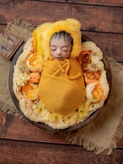 A full overhead view of this rustic yellow-themed shoot, with the baby nestled in a wooden bowl on a burlap mat.