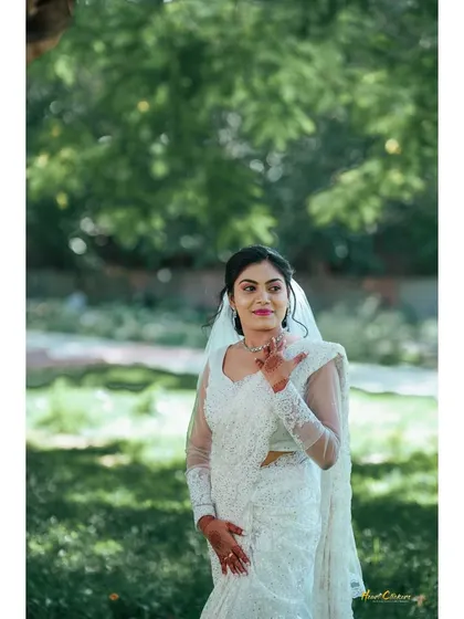 A graceful portrait of a Christian bride in her white saree and veil, set against a soft, natural background.