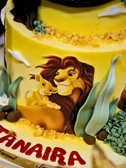 A close-up of the incredible, hand-painted Lion King cake, showing the tender moment between Mufasa and Simba.