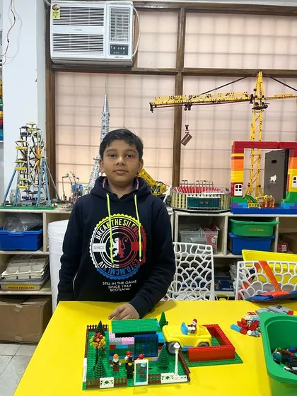 A student displays his LEGO park scene. In the background, our classroom's collection of advanced models inspires students to think bigger.