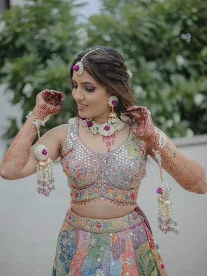 This bride is ready for her Mehendi in a multi-coloured lehenga. We created this custom floral set with purple flowers and intricate pearl work to complement her vibrant outfit.