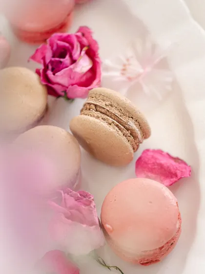 A dreamy, high-key shot of delicate pink and brown macarons surrounded by rose petals. This showcases my ability to create soft, airy, and romantic visuals for patisseries and dessert brands.