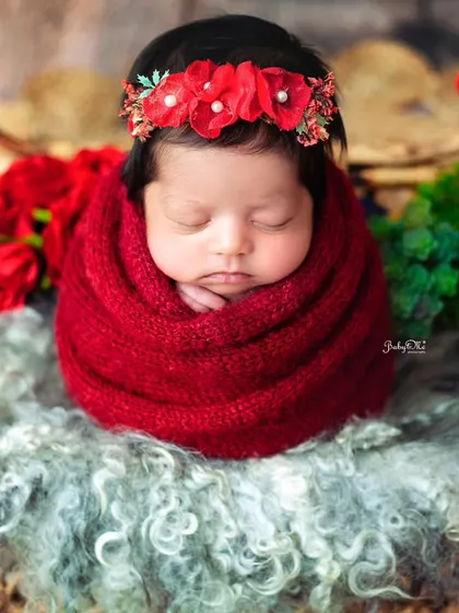 Wrapped snugly in a bold red knit, this newborn looks so cozy and content. The color contrast with the floral headband makes the image pop.