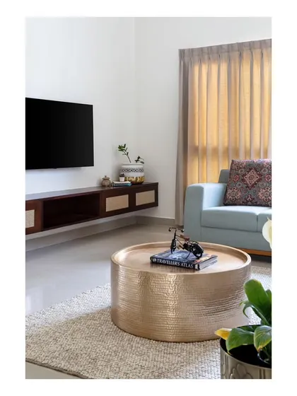 The upper-floor family lounge, a tranquil retreat for the family to unwind. The space features a sleek floating TV unit, revamped vintage sofas, and a captivating center table made of beaten brass.