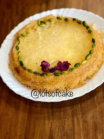 My homemade Kunafa, a cherished Middle Eastern dessert. It has a crispy, shredded phyllo dough exterior, a sweet cheese filling, and is garnished with pistachios and rose petals.