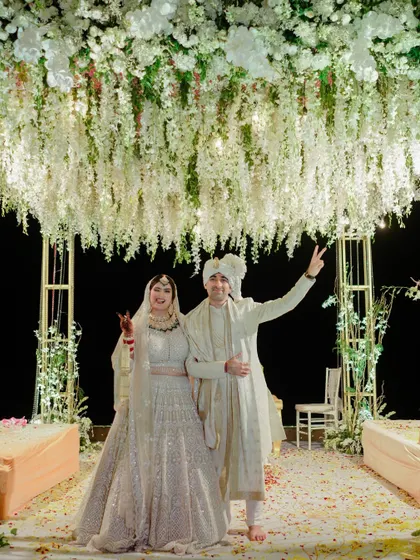 A triumphant moment under a ceiling of flowers. The couple, hand in hand, celebrates after their ceremony, their happy expressions perfectly captured.