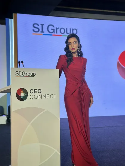 Posing by the lectern, her makeup looks polished and professional. The bold red lip is a classic choice that exudes confidence, while the softly sculpted cheeks add dimension for the camera.