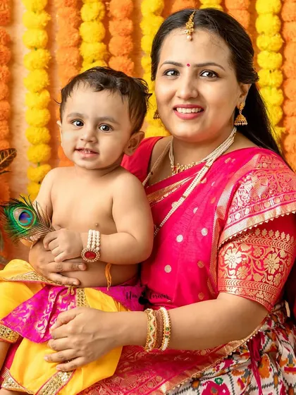 This mother holds her baby, who is holding a peacock feather, a signature element of Lord Krishna.