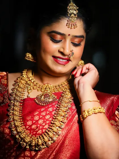A candid moment capturing the bride's happy glow. The focus here is on the shimmering gold and bronze eyeshadow that catches the light beautifully, paired with a soft red lip.