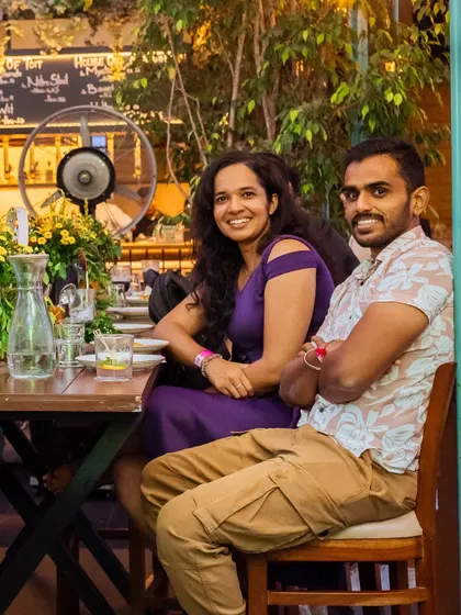 A couple enjoying the evening at one of our outdoor tables. The lush greenery and warm lighting create a romantic and relaxed atmosphere.