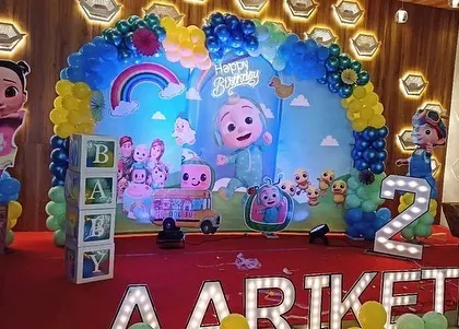 A closer look at the Cocomelon birthday stage, focusing on the central backdrop, 'BABY' blocks, and the colorful balloon arch.
