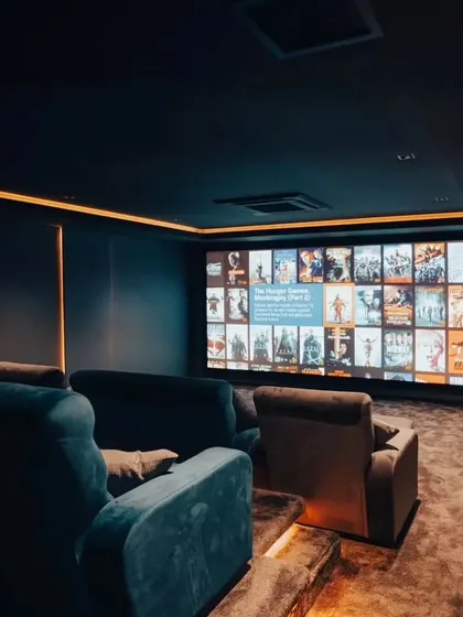 A look at a finished project with plush, comfortable seating and a large screen ready for movie night. The warm overhead lighting creates an inviting atmosphere.