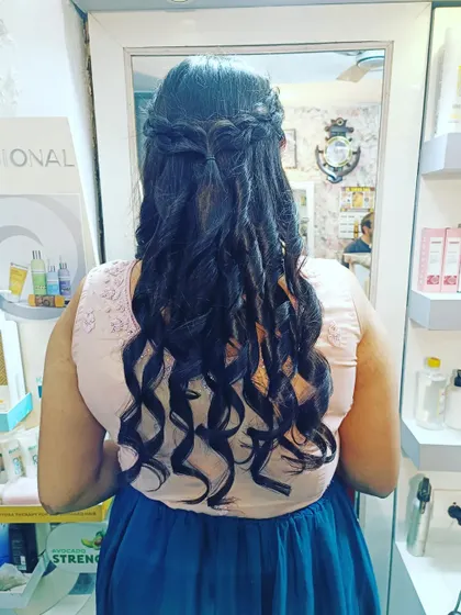 This half-up look combines a waterfall braid with structured curls, creating a beautiful and intricate style perfect for a wedding guest.