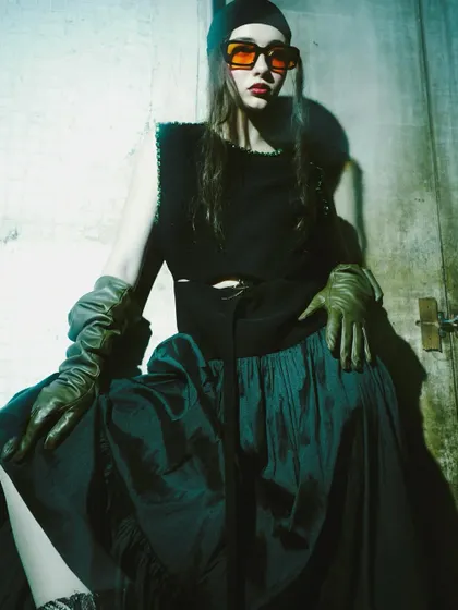 A high-contrast, moody shot with the model in orange-tinted sunglasses. The harsh lighting and shadows create a gritty, edgy vibe that is both fashionable and cinematic.