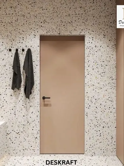 This contemporary bathroom uses terrazzo on the floors and walls, paired with a simple beige door and black hardware for a clean, minimalist look.