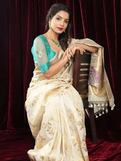 A picture of pure elegance, this model pairs a cream and gold Banarasi saree with a delicate green beaded necklace and matching earrings.
