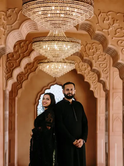 A stunning pre-wedding shoot in a grand location. The couple's coordinated black outfits are complemented by elegant, subtle makeup.