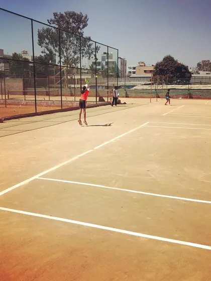 A player serves on one of the well-maintained courts at the new Tennis360 Academy in Thindlu, Bangalore.