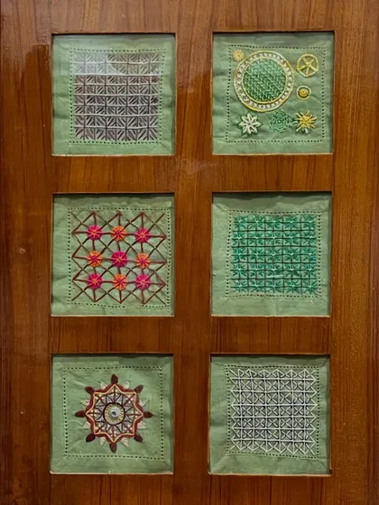 Another set of six framed embroidery samplers, this time on a green background. Each square showcases a different stitch or pattern, celebrating the diversity of the craft.