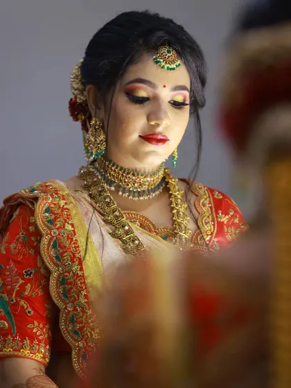 A reflection of bridal beauty. This shot gives a closer look at the detailed embroidery on the red blouse, featuring parrots and floral designs that bring the concept of nature to life.