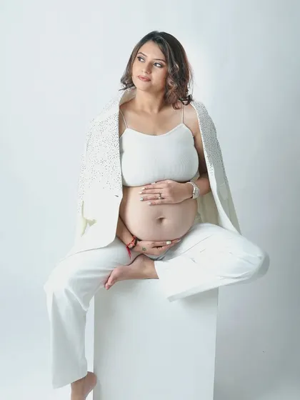 A powerful solo portrait of a mother to be in a chic all white outfit. The open blazer and confident pose celebrate her strength and beauty during pregnancy.