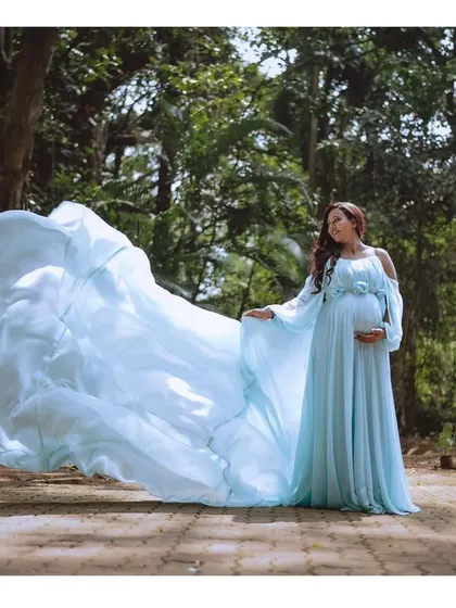 A full view of the magical powder blue maternity gown. The flowing trail creates a breathtaking effect, perfect for an outdoor photoshoot.