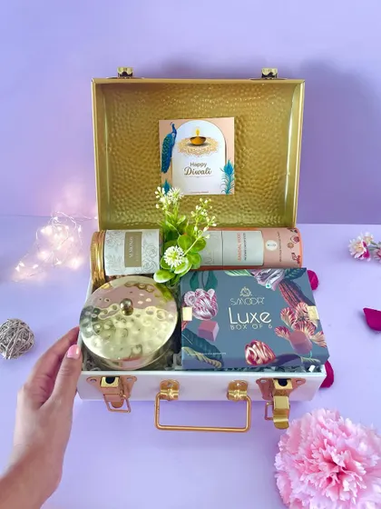 A hand reaching into our premium metal trunk, giving a sense of the interactive and delightful experience of receiving one of our hampers.