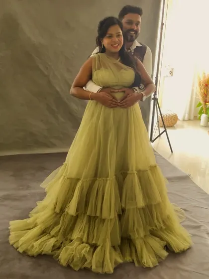 A behind-the-scenes look at a couple's portrait, showing the studio lighting setup and the full sweep of the elegant green gown.