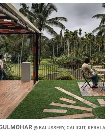 The rooftop terrace at Gulmohar is designed as an outdoor living space, complete with a wooden deck and seating area, offering panoramic views of the surrounding palm groves.