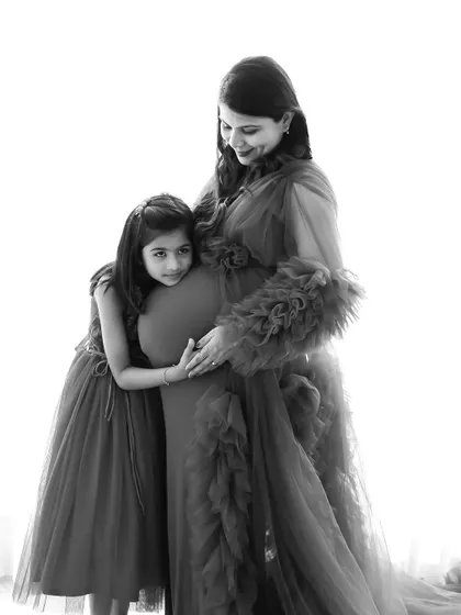 A touching black and white photo of an older sister hugging her mother's baby bump. We aim to capture these precious sibling bonding moments before the new baby arrives.