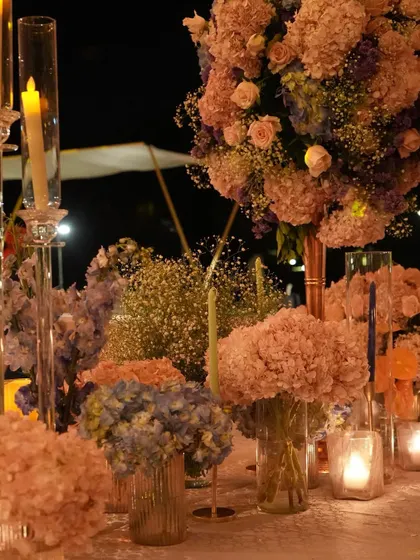 A soft-focus shot of the tablescape, capturing the dreamy and romantic atmosphere. The mix of pink and blue hydrangeas with delicate baby's breath creates a cloud-like effect.