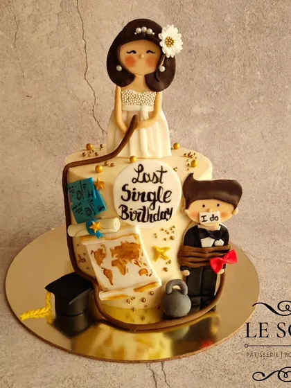 This "Last Single Birthday" cake tells a fun story. The 1 kg Honey Almond cake is decorated with 3D fondant figurines of the bride-to-be and her captive groom, along with elements representing her life and travels.