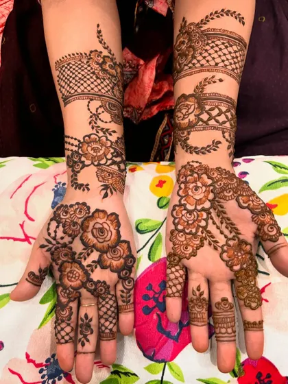 A stunning floral henna design with intricate netting and cuff details on the wrist. The patterns are different yet complementary on each hand, showcasing my ability to customize designs.