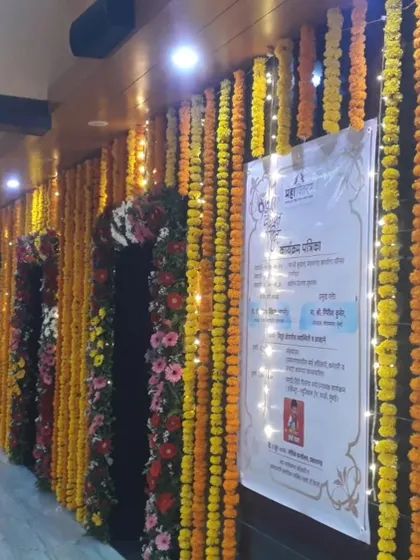A wall decorated with strings of marigold flowers and fairy lights for a traditional event, creating a warm and welcoming atmosphere.