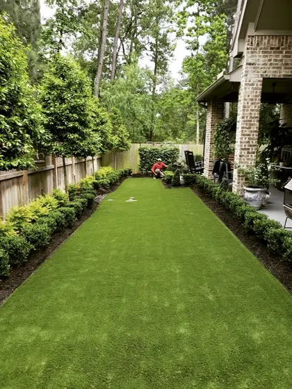 A long, rectangular lawn bordered by neat hedges. This image shows our team at work, demonstrating the care we take in maintaining and perfecting every landscape project.