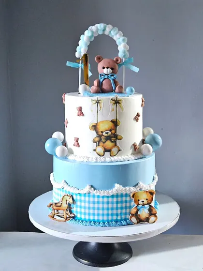 This super cute two-tier teddy bear cake was a same-day order. The design features a blue and white gingham pattern, a handmade teddy bear topper, and other adorable teddy accents.