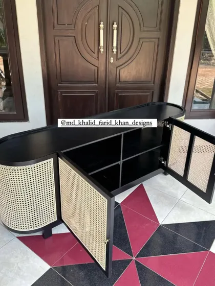 This sleek, oval-shaped console cabinet features a black finish contrasted with natural hand-woven cane doors. The interior reveals ample shelving, making it a perfect custom storage solution for a dining or living room.