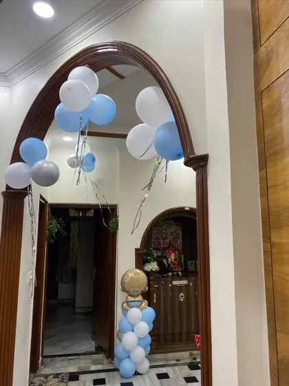 A welcoming entrance for a baby boy's celebration, with balloon bunches and a small balloon pillar featuring a baby-themed foil balloon.