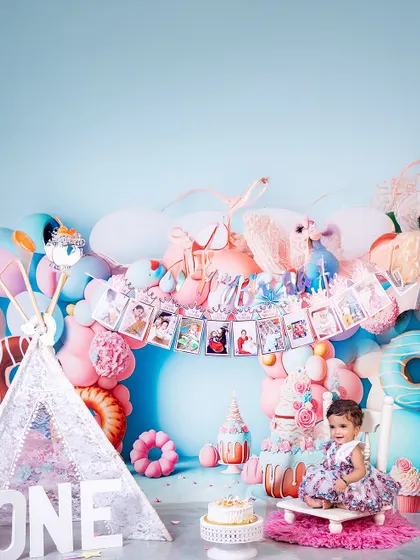 Sitting like a little queen on her throne, this one-year-old is surrounded by a pastel dreamscape. The photo banner above tells the story of her incredible first year.