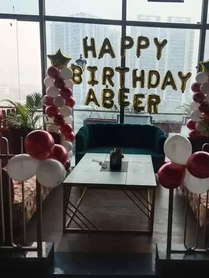 This 'Happy Birthday Abeer' setup uses classic red and white balloon pillars to create a celebratory corner in a modern restaurant.