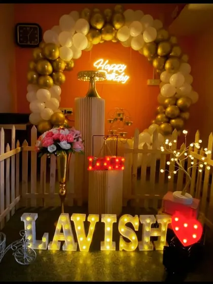 A simple and elegant birthday setup with a gold and white balloon arch, perfect for a sophisticated celebration at home.