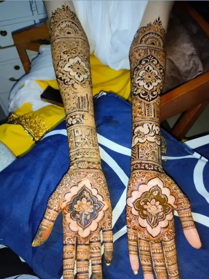 Full-arm bridal mehndi featuring lotus motifs on the palms and intricate patterns extending to the elbows. A classic and elegant choice for any bride.