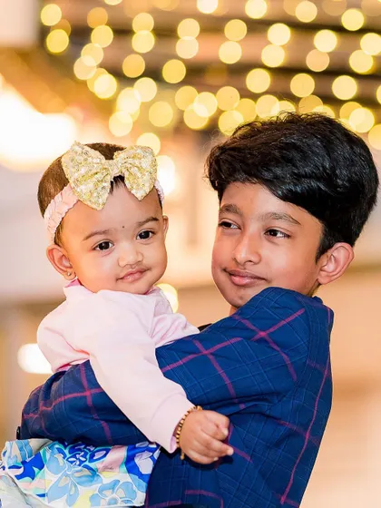 A sweet moment between an older brother and his baby sister at their joint birthday party. Capturing sibling bonds is one of the highlights of our work.