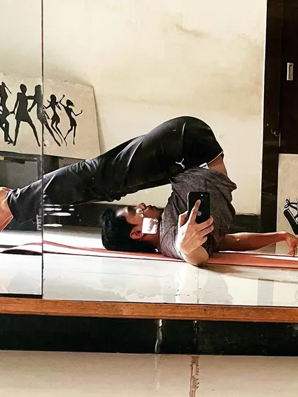 A mirror selfie of the Plow Pose, showing the deep spinal flexion this yoga asana provides.