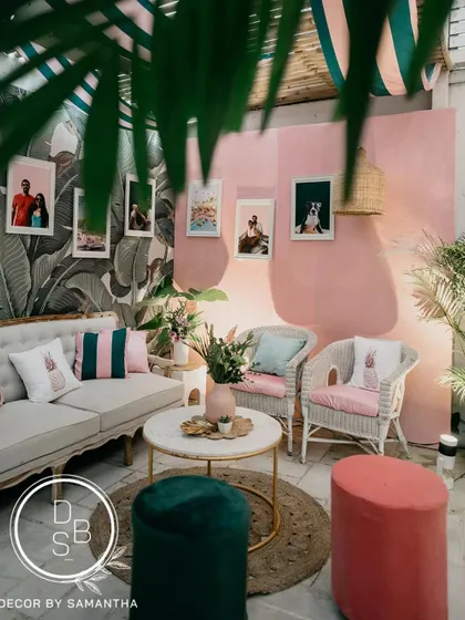 This cozy corner of the brunch setup features a pink textured wall, wicker chairs, and personal photos of the couple, making the space feel intimate and story-driven.