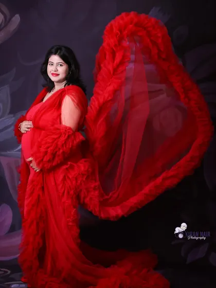 A dynamic shot of a mom-to-be in a red gown with the ruffled train tossed for a dramatic, flowing effect.