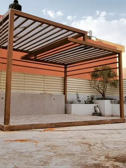 A work-in-progress shot of a custom two-tiered pergola. This image shows the wooden frame being installed on a raised platform, highlighting the structural work before completion.