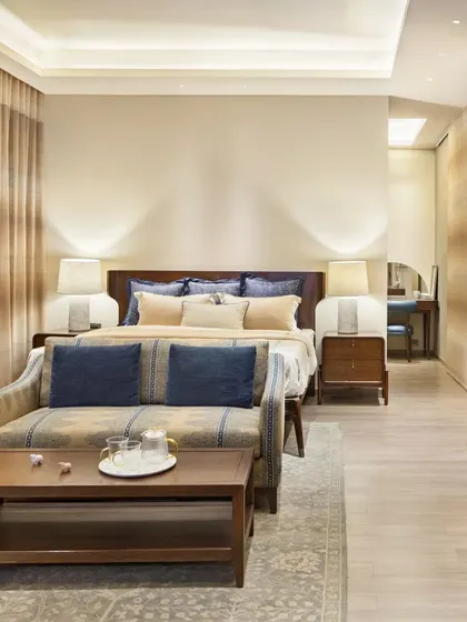 A serene master bedroom at the Max128 apartment. The design combines warm wood tones, soft textiles, and subtle Indian motifs to create a peaceful and luxurious personal retreat.