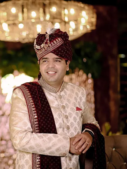 A smiling portrait of the groom, Saksham, in his ivory and maroon sherwani.